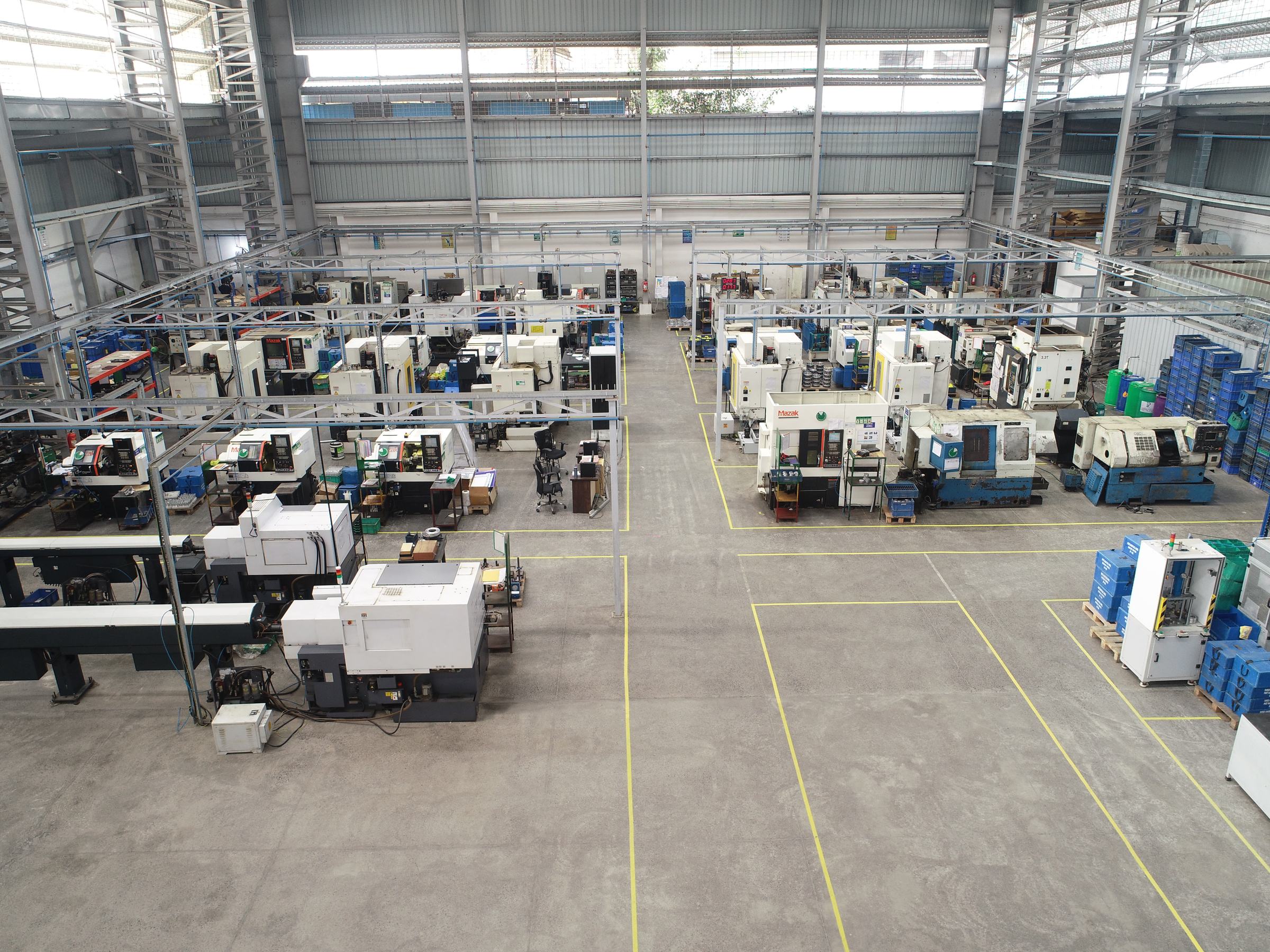 Aerial view of a CNC turning shop floor: rows of CNC turning centres with bar feeders and blue bins